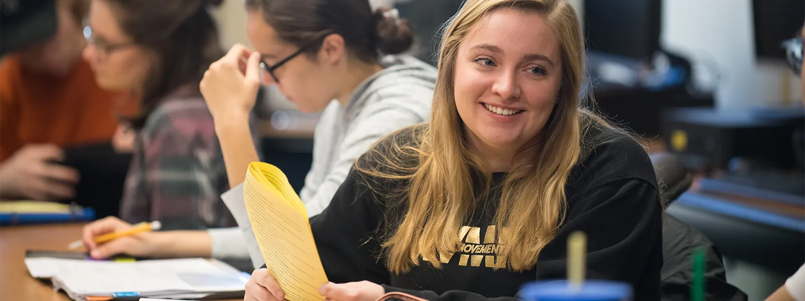 estudiante en clase con papel en mano