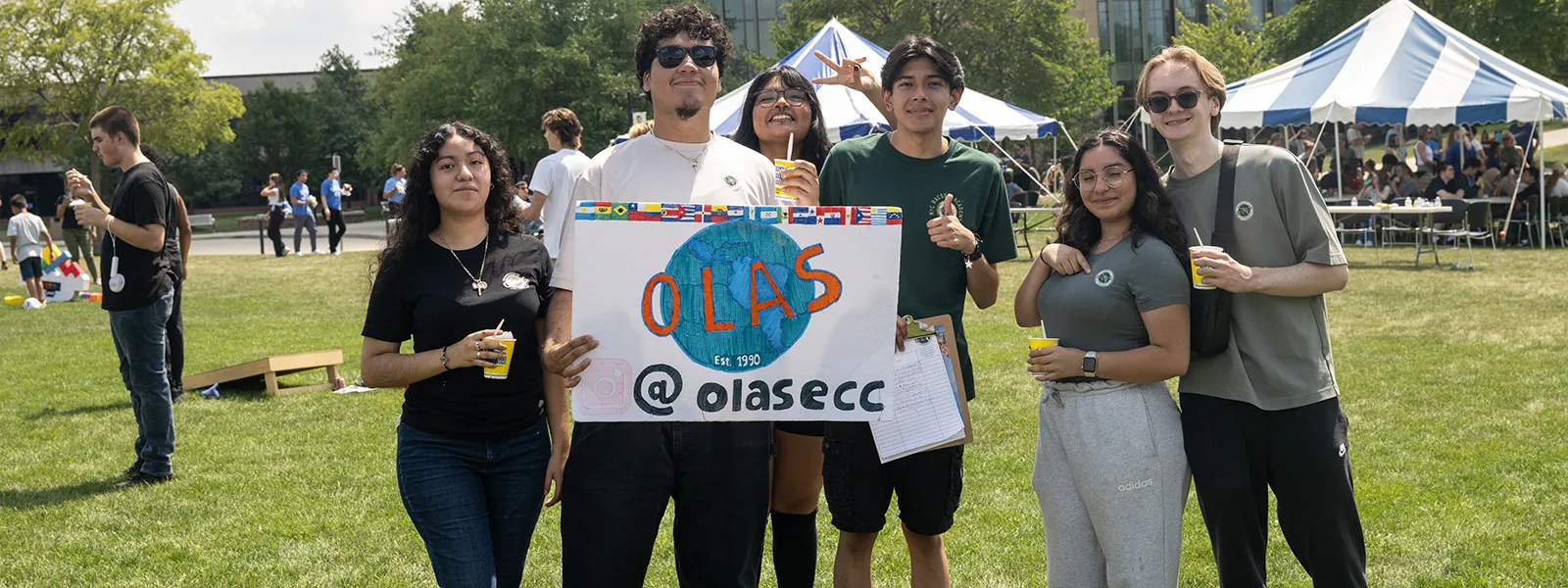 students holding an organization of Latin American students sign on a lawn