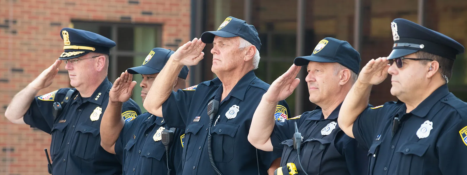 Oficiales del Departamento de Policía de Elgin CC saludan durante la presentación de banderas de la guardia de color.