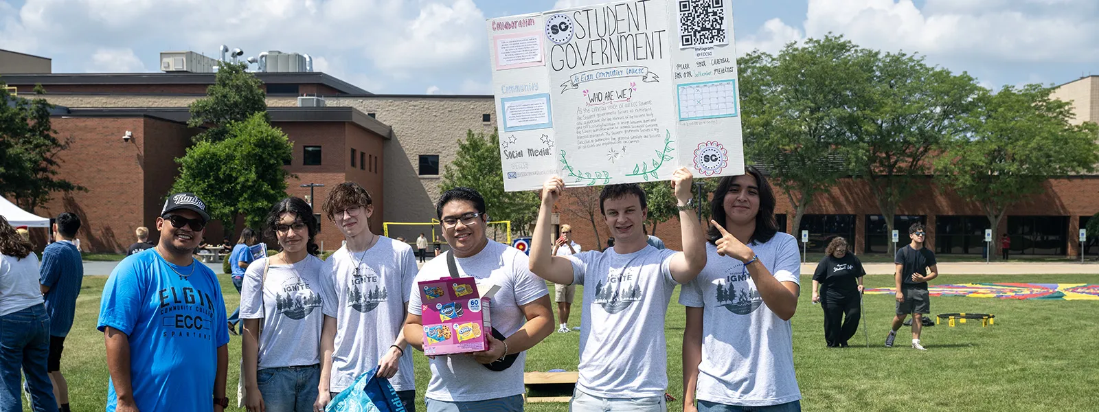 students smiling, looking forward, holding a sign saying student government