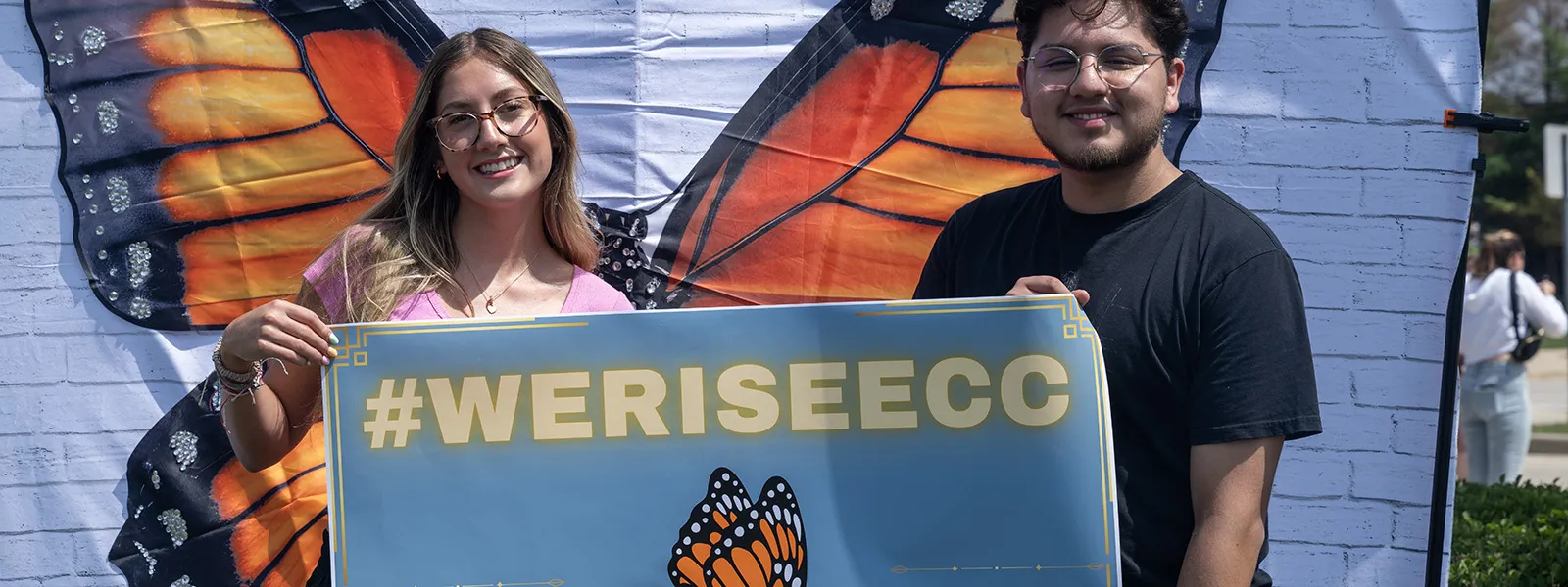 Students stand in front of a butterfly on a poster