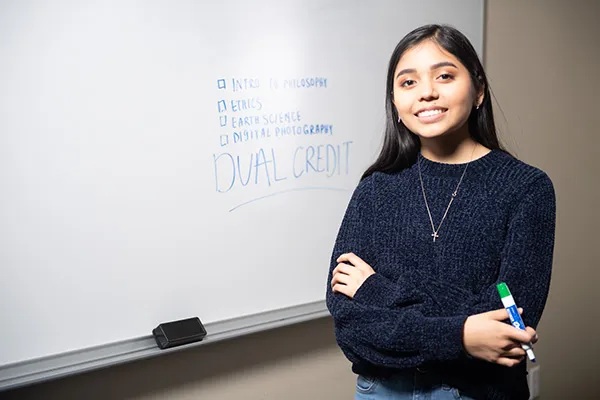 High school student posing in front of a board