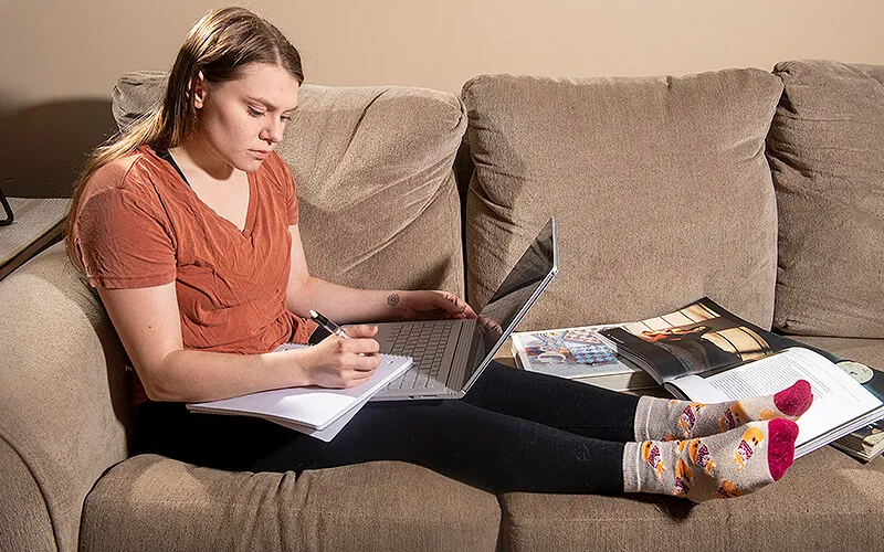 Female student on couch working on her laptop computer.