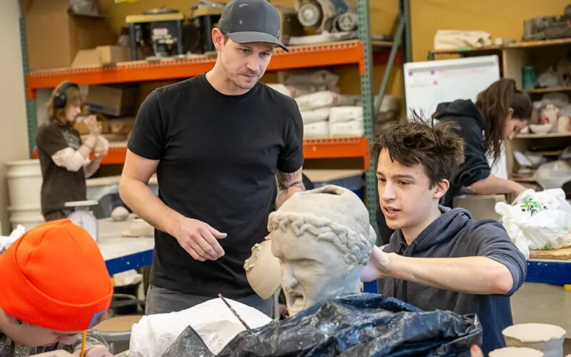 The teacher works with the student in the sculpting class