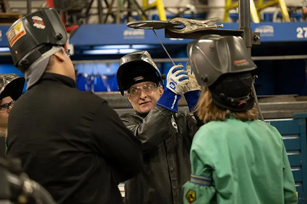 Students working with a teacher in welding class