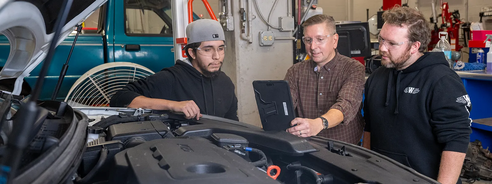 students with instructor looking under the hood of a car