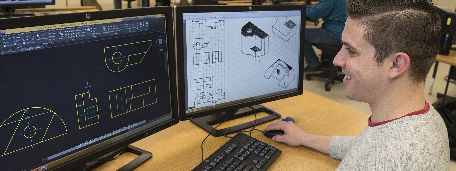 A worker at the desk working on CAD software.