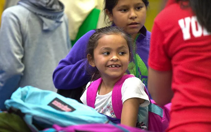 A young student holds a backpack