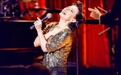 Angela Ingersoll sings into a microphone while portraying Judy Garland