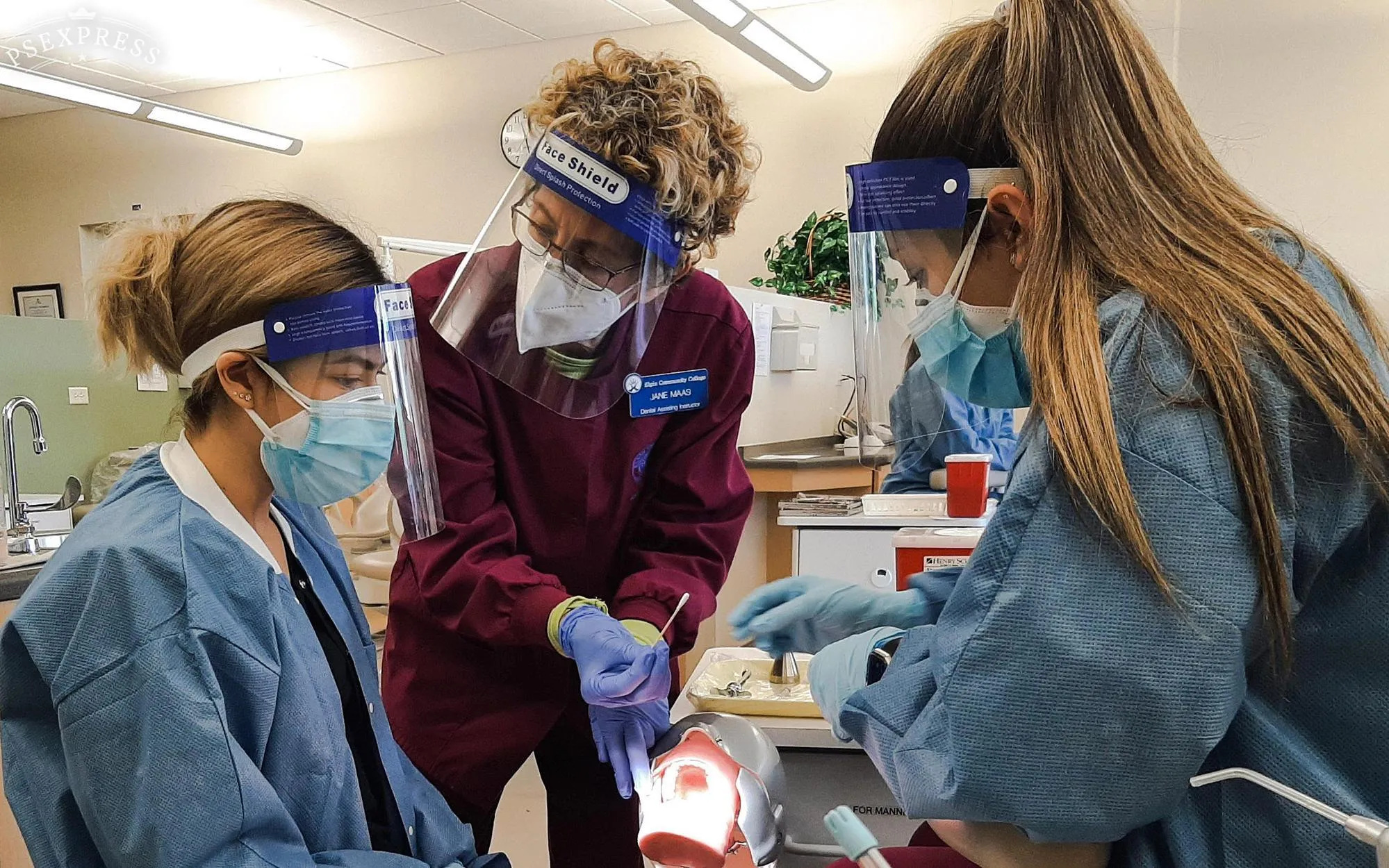 Jane Maas, dental assisting adjunct faculty, demonstrates anesthetic application for two students