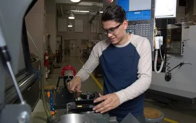 A student works with a piece of manufacturing equipment in ECC's shop facilities