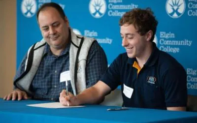 A student apprentice signs his offer from a local company.