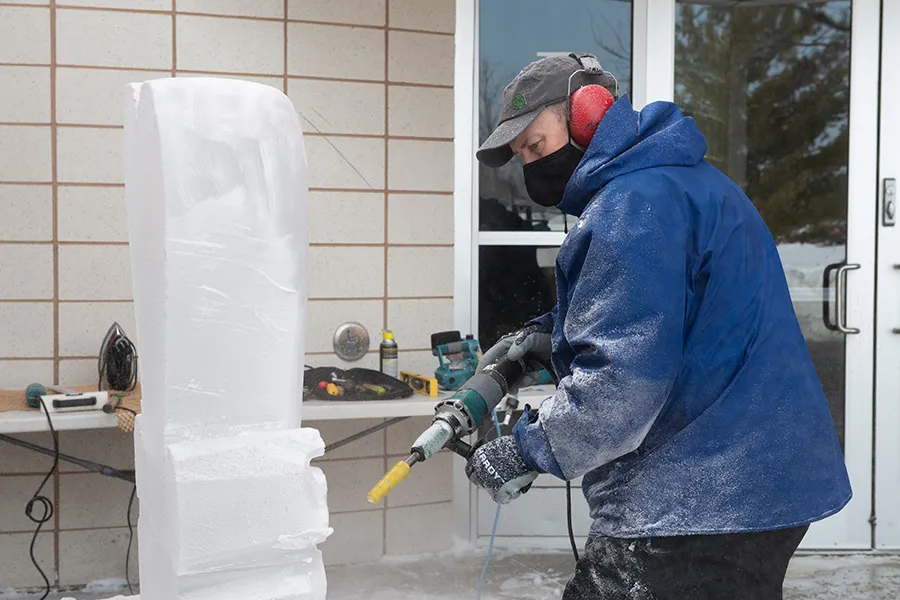 Person with power tool sculpting ice