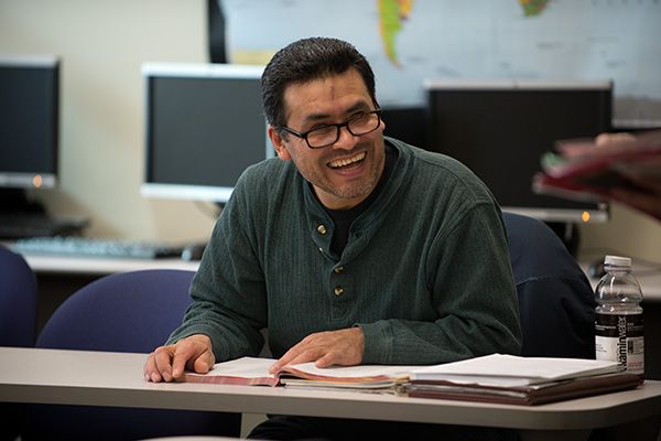 A student sitting in a classroom, smiling at camera